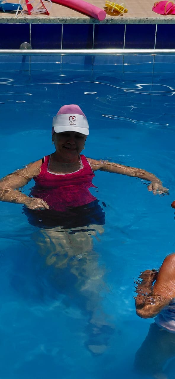 Aluna com boné da ASBEM durante exercício na piscina