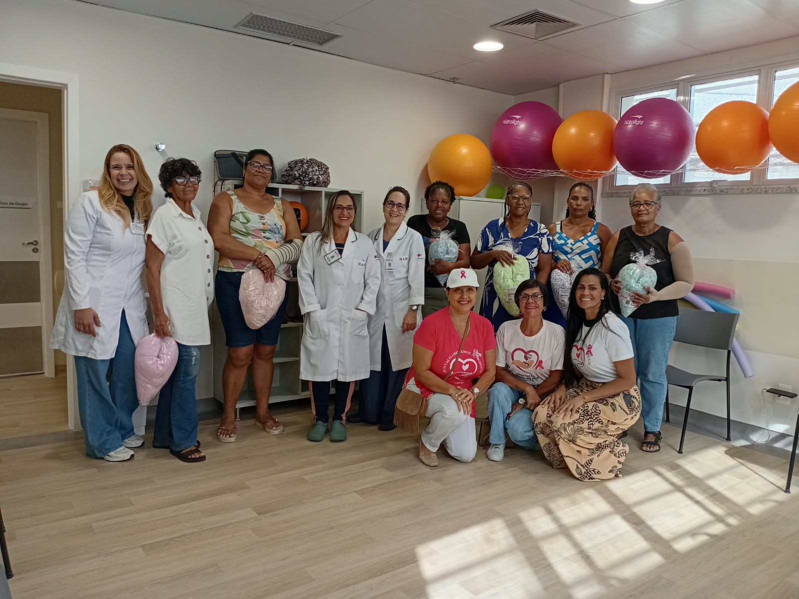 Pacientes com almofadas de coração ao lado da equipe de saúde e das voluntárias da ASBEM