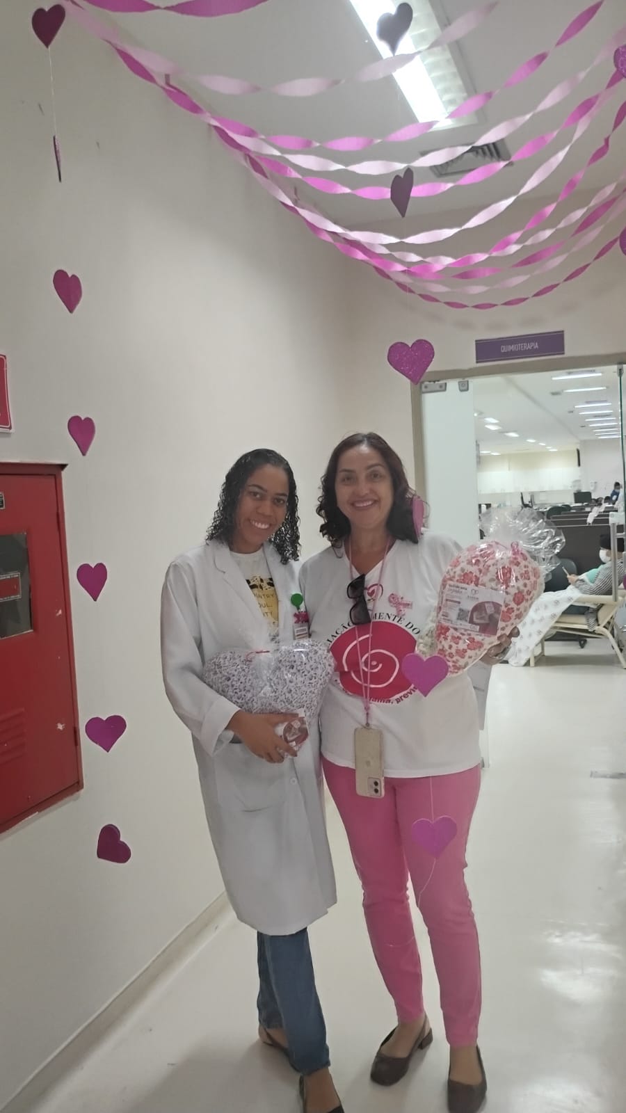 Equipe do Hospital da Mulher e voluntária da ASBEM no corredor da quimioterapia enfeitado com corações