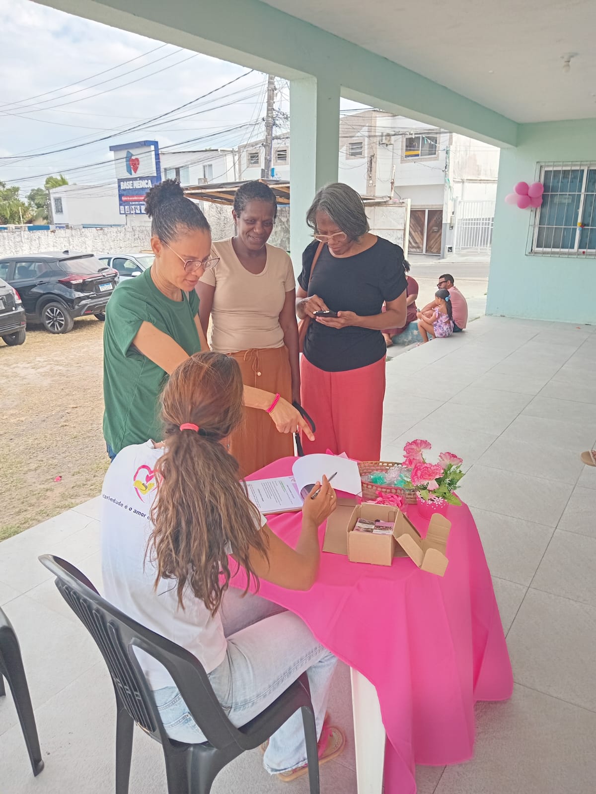 Voluntária da ASBEM recebe mulheres na mesa de recepção do encontro