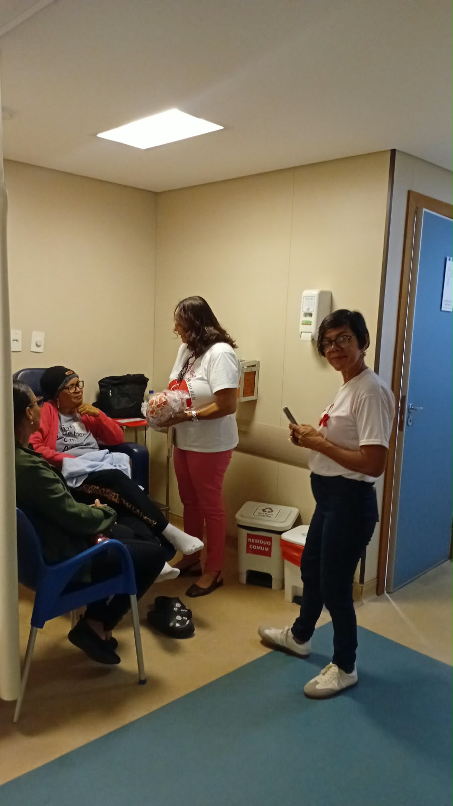 Voluntárias da ASBEM conversam com paciente e acompanhante durante a sessão de quimioterapia