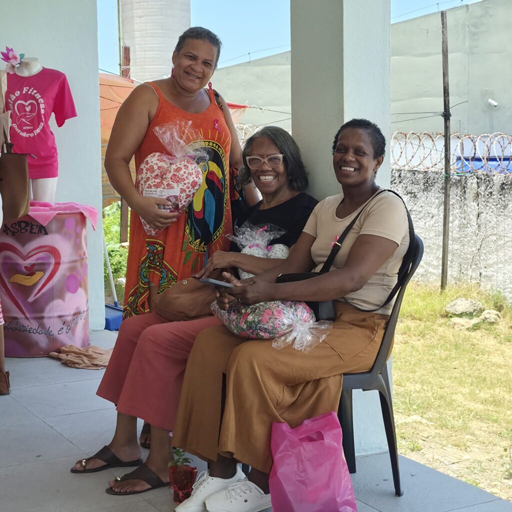 Mulheres sorridentes com almofadas de coração no encontro de acolhimento da ASBEM